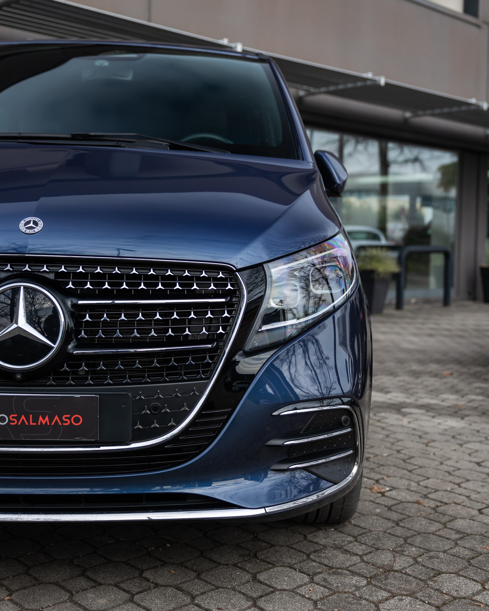 Muso di monovolume Mercedes blu scuro con calandra a stelle cromate e portatarga AutoSalmaso su autobloccanti